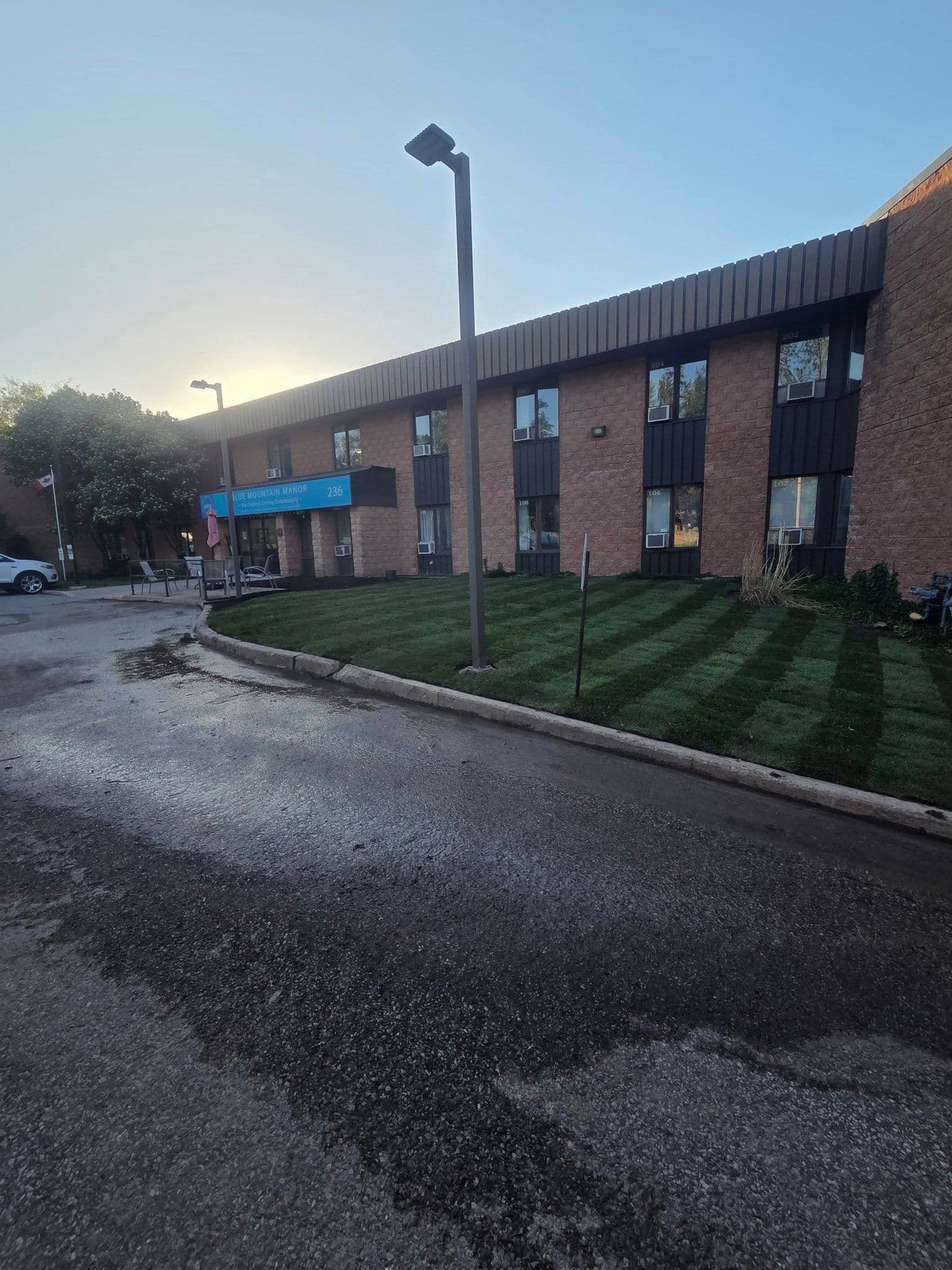 Multi-unit residential building with freshly mowed, striped grounds at dusk