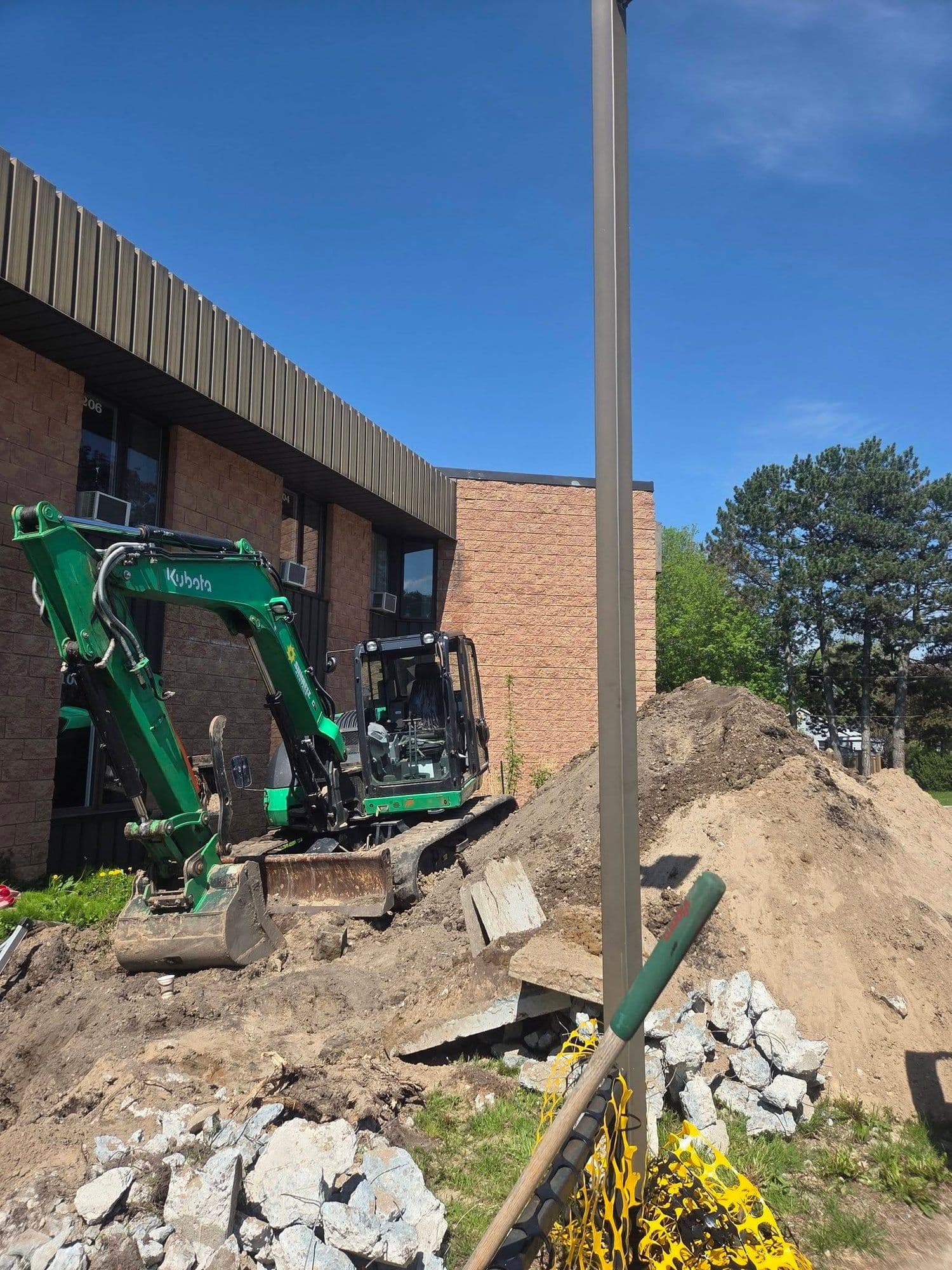 Compact excavator digging beside a commercial building